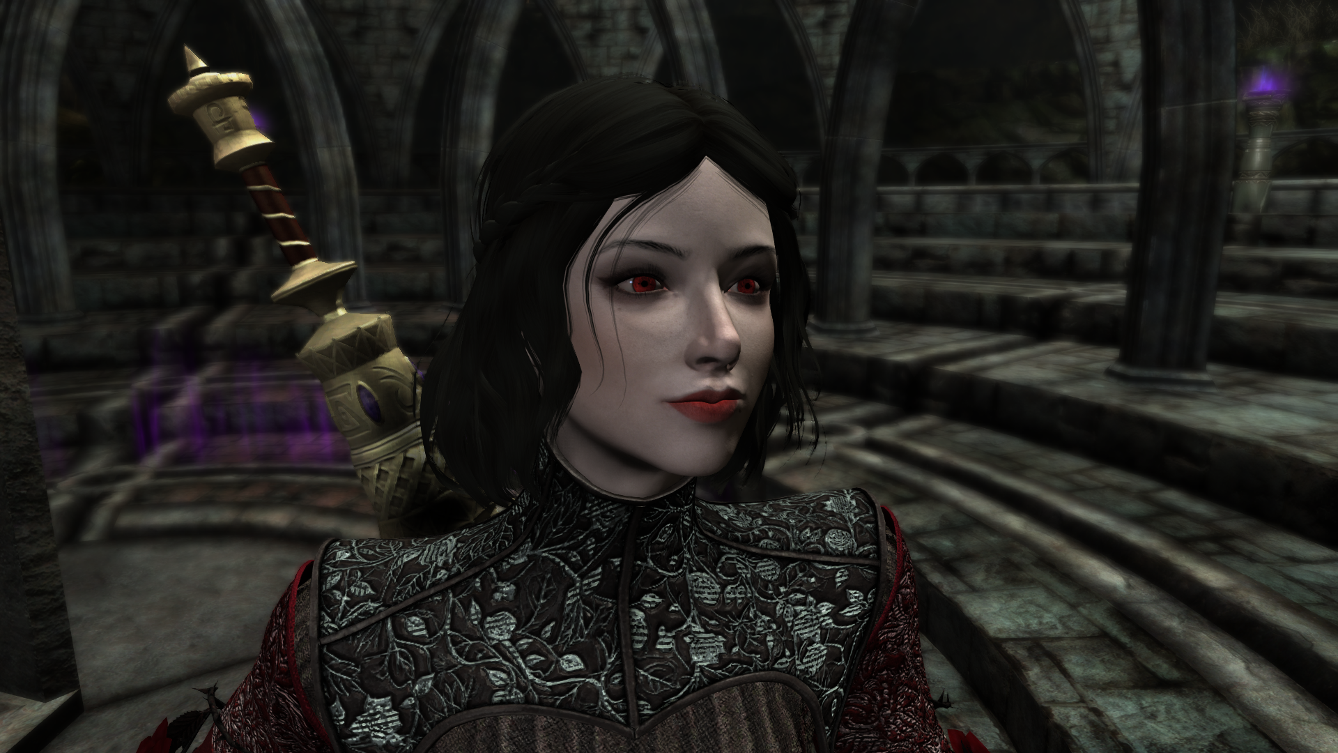Serana the vampire from Skyrim's Dawnguard DLC, dressed in the "Grievous Rose" outfit mod, and bearing the modified looks of "Trueblood Serana"

A close up of her face shows her raven black, short bobbed(?) hair and telltale crimson eyes of a vampire.   She carries the Elder Scroll of Blood on her back.